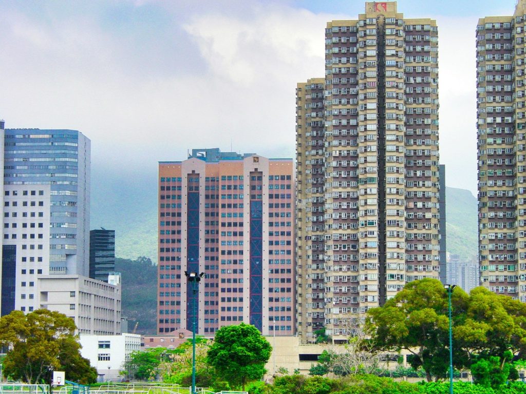 high rise buildings near green trees under white clouds during daytime