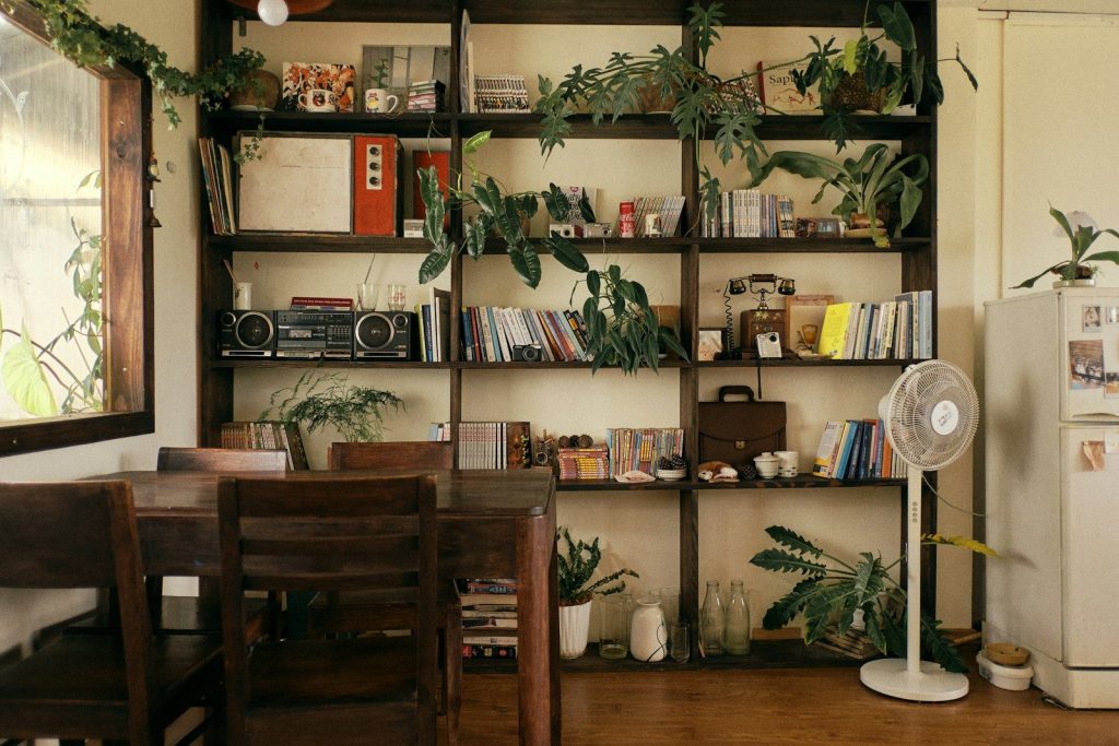 A cozy room with a bookshelf, plants, and dining table